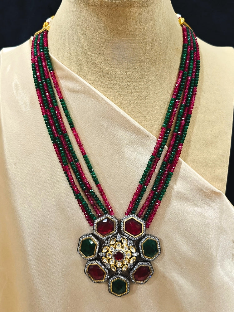 Close-up of an ornate traditional Diamond Ruby Red and Green jewellery set and earrings with Kundan, American Diamond, Monalisa Stones and Crystal Beads. A  luxury American diamond necklace set styled beautifully for a wedding guest look in India. Elegant festive look with a high-quality imitation American diamond necklace set.