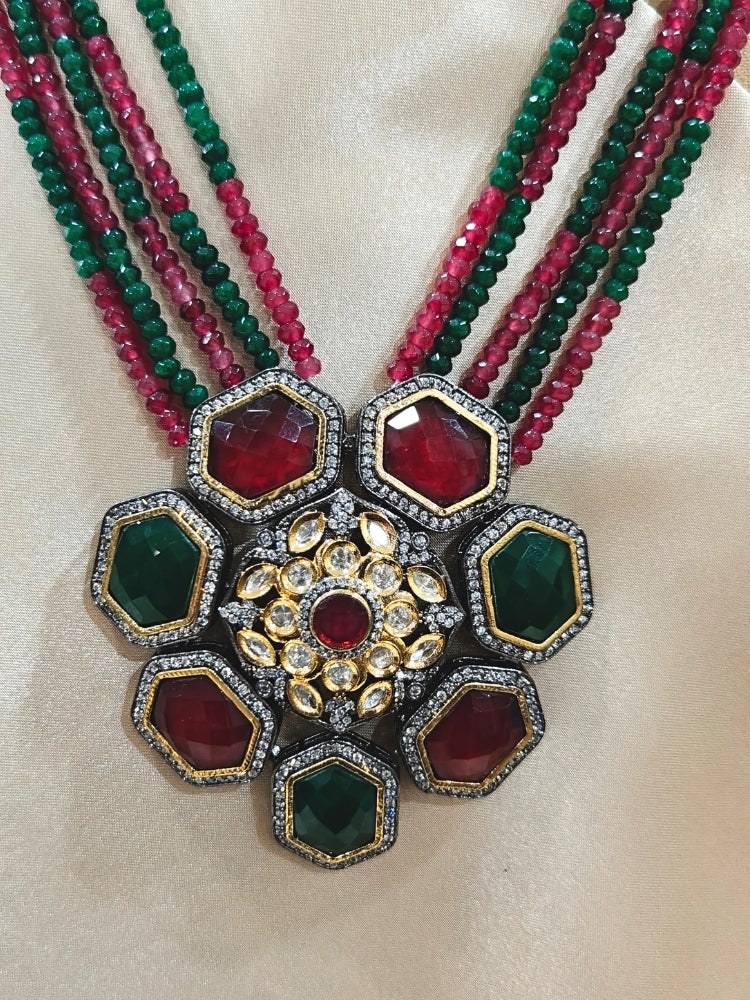 Close-up of an ornate traditional Diamond Ruby Red and Green jewellery set and earrings with Kundan, American Diamond, Monalisa Stones and Crystal Beads. A  luxury American diamond necklace set styled beautifully for a wedding guest look in India. Elegant festive look with a high-quality imitation American diamond necklace set.