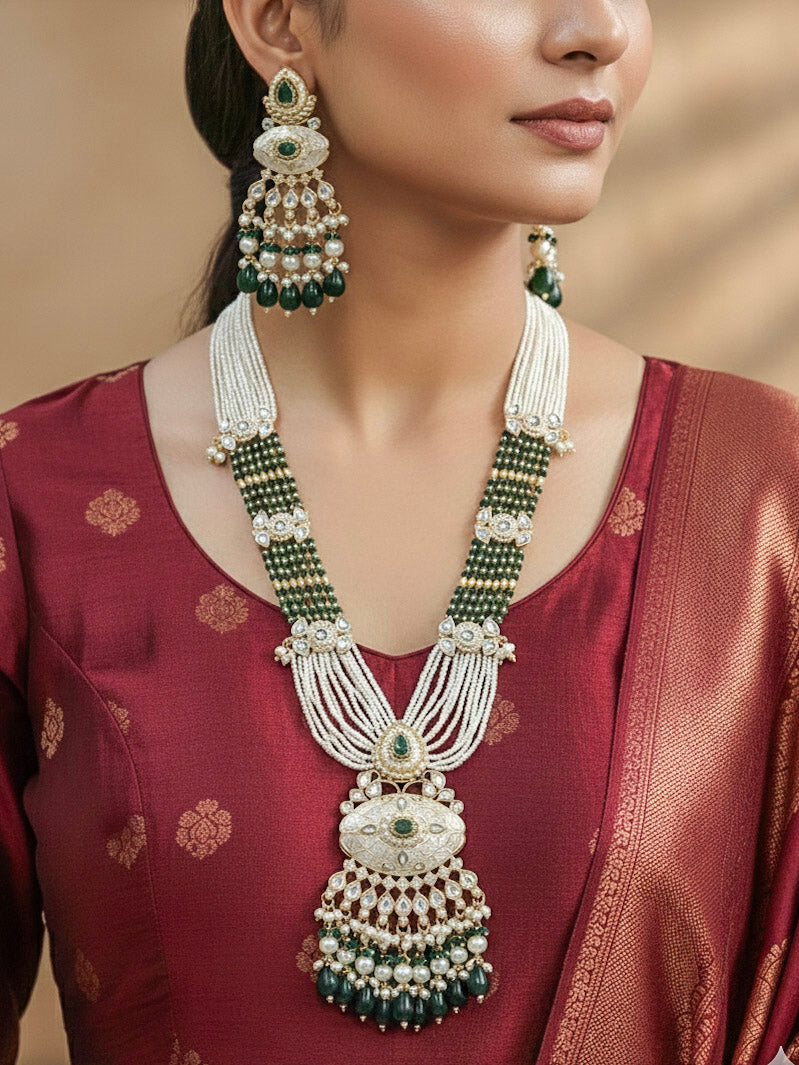 Close-up of a woman wearing an ornate traditional Dark Green Rajwadi gold Long jewellery set and earrings  with Pearls, Beads, Meenakari and Moissanite Kundan. Woman styled in a royal Rajwadi artificial necklace set for a traditional Indian wedding. Reception party look featuring a statement Rajwadi necklace.