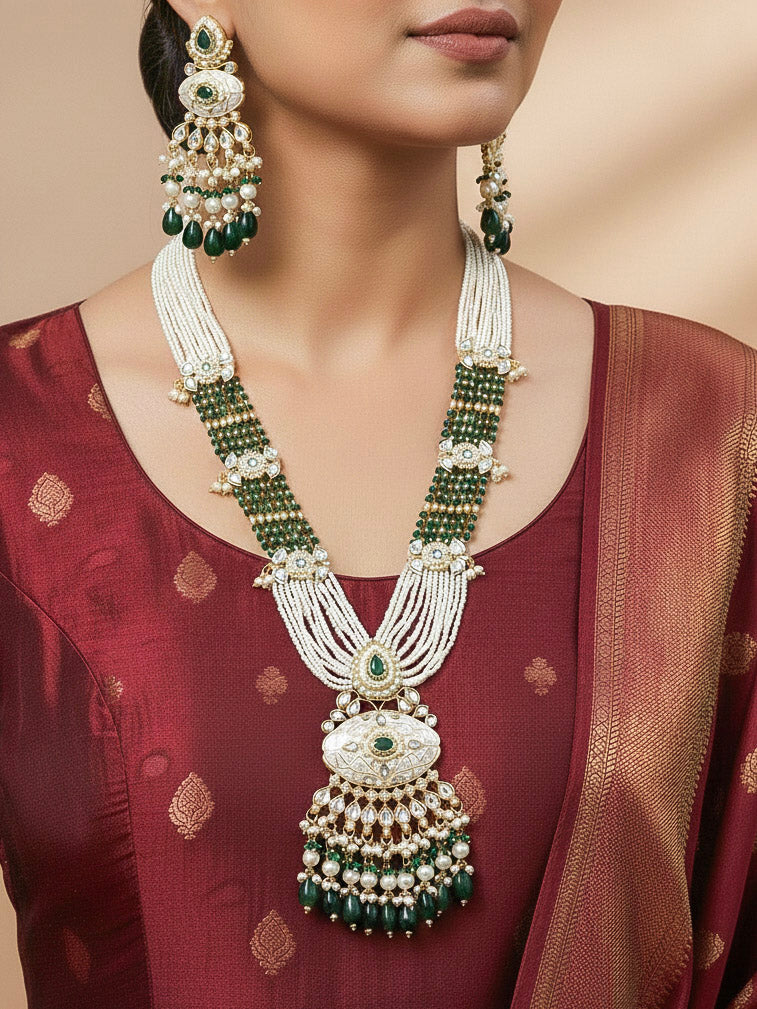 Close-up of a woman wearing an ornate traditional Dark Green Rajwadi gold Long jewellery set and earrings  with Pearls, Beads, Meenakari and Moissanite Kundan. Woman styled in a royal Rajwadi artificial necklace set for a traditional Indian wedding. Reception party look featuring a statement Rajwadi necklace.