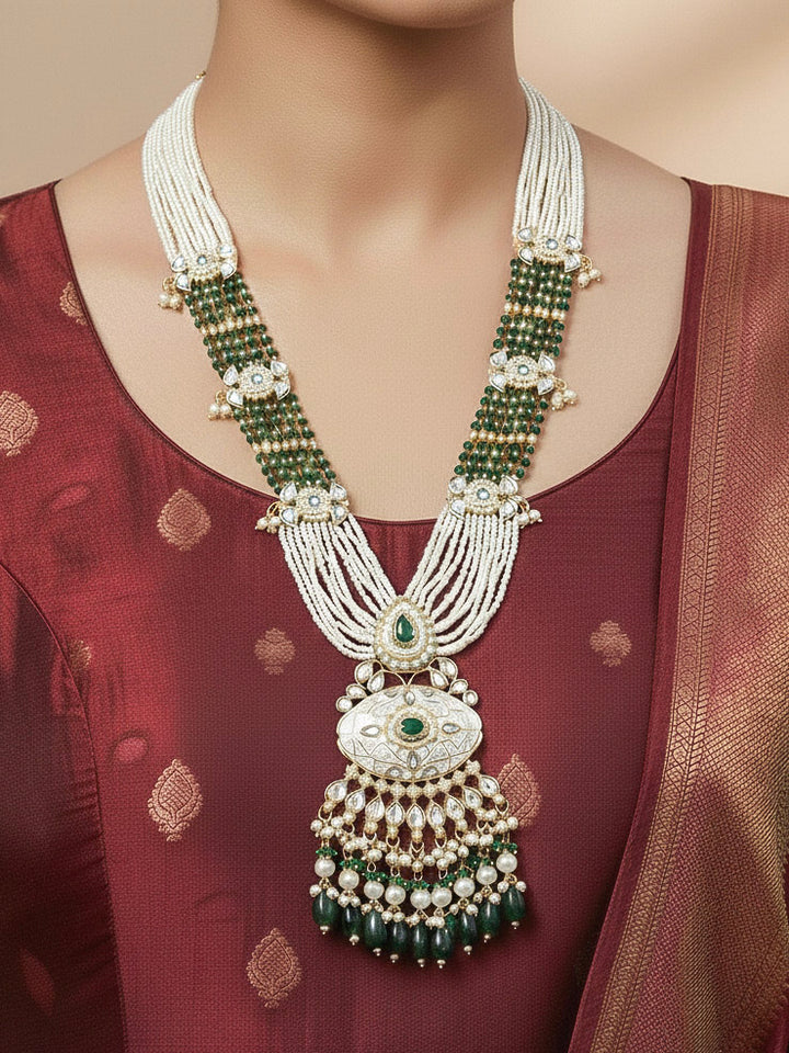 Close-up of a woman wearing an ornate traditional Dark Green Rajwadi gold Long jewellery set and earrings  with Pearls, Beads, Meenakari and Moissanite Kundan. Woman styled in a royal Rajwadi artificial necklace set for a traditional Indian wedding. Reception party look featuring a statement Rajwadi necklace.