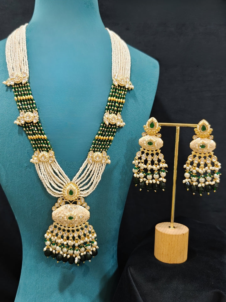 Close-up of a woman wearing an ornate traditional Dark Green Rajwadi gold Long jewellery set and earrings  with Pearls, Beads, Meenakari and Moissanite Kundan. Festive Diwali outfit enhanced with a Rajwadi artificial necklace. Close-up of a premium Rajwadi artificial necklace under 10000. Perfect Rajwadi necklace set for weddings and festivals.