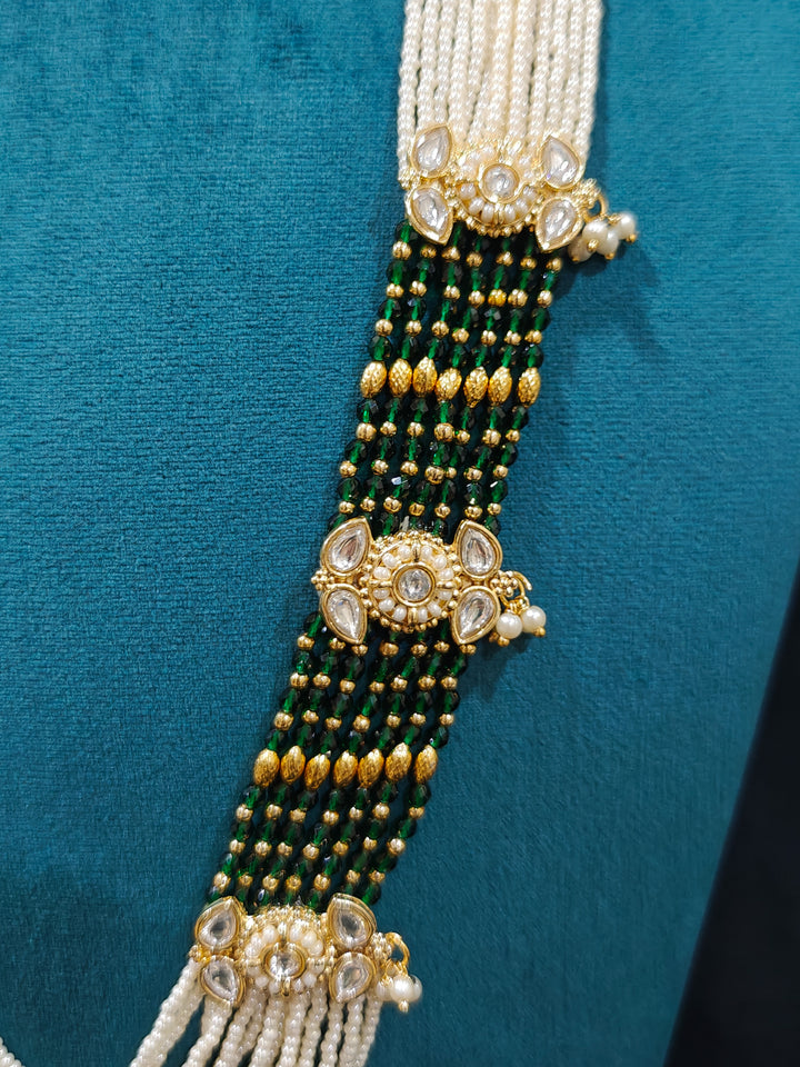 Close-up of a woman wearing an ornate traditional Dark Green Rajwadi gold Long jewellery set and earrings  with Pearls, Beads, Meenakari and Moissanite Kundan. Festive Diwali outfit enhanced with a Rajwadi artificial necklace. Close-up of a premium Rajwadi artificial necklace under 10000. Perfect Rajwadi necklace set for weddings and festivals.