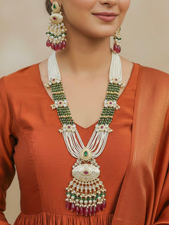 Close-up of a woman wearing an ornate traditional Ruby Pink and Green Rajwadi gold Long jewellery set and earrings  with Pearls, Beads, Meenakari and Moissanite Kundan. Woman styled in a royal Rajwadi artificial necklace set for a traditional Indian festives. Woman pairing a Rajwadi necklace with a Anarkali.