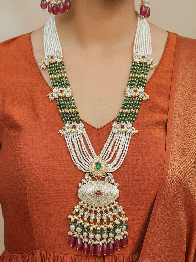 Close-up of a woman wearing an ornate traditional Ruby Pink and Green Rajwadi gold Long jewellery set and earrings  with Pearls, Beads, Meenakari and Moissanite Kundan. Woman styled in a royal Rajwadi artificial necklace set for a traditional Indian festives. Woman pairing a Rajwadi necklace with a Anarkali.