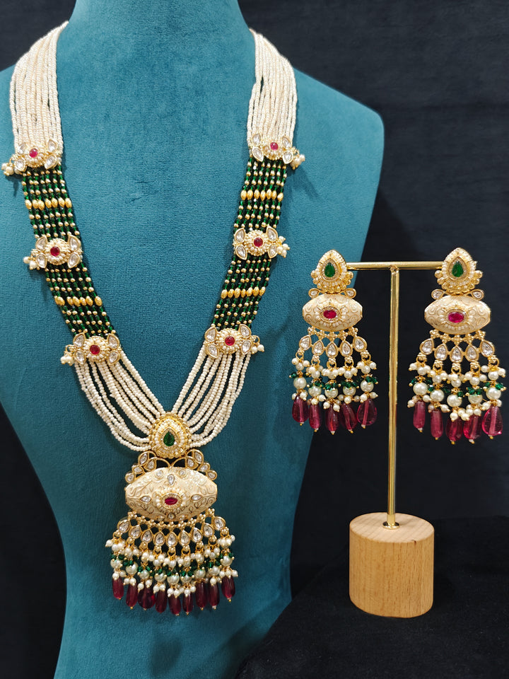 Close-up of an ornate traditional Ruby Pink and Green Rajwadi gold Long jewellery set and earrings  with Pearls, Beads, Meenakari and Moissanite Kundan. Festive look completed with a luxury Rajwadi imitation necklace. Close-up of a premium Rajwadi artificial necklace under 10000.