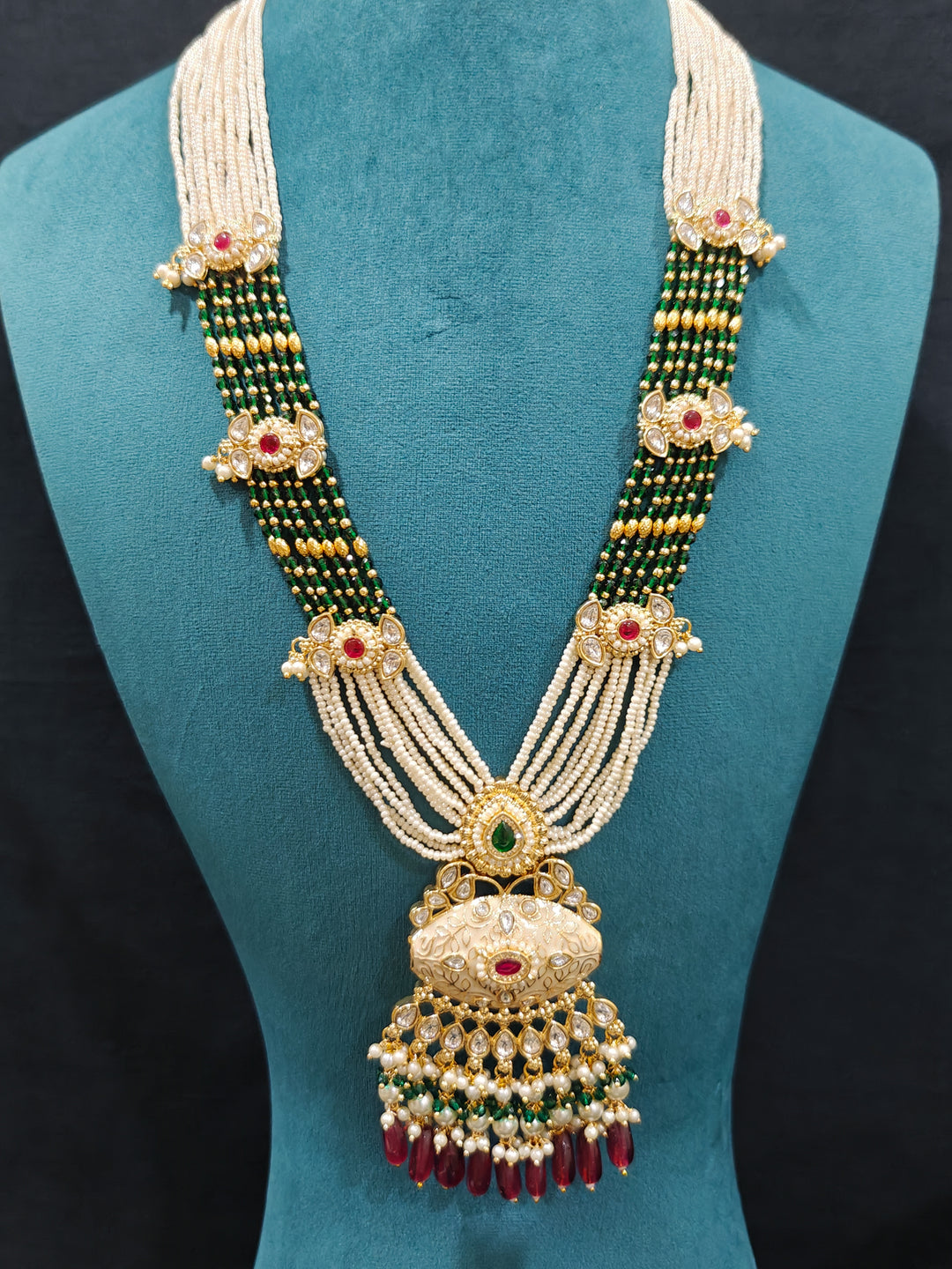 Close-up of an ornate traditional Ruby Pink and Green Rajwadi gold Long jewellery set and earrings  with Pearls, Beads, Meenakari and Moissanite Kundan. Festive look completed with a luxury Rajwadi imitation necklace. Close-up of a premium Rajwadi artificial necklace under 10000.