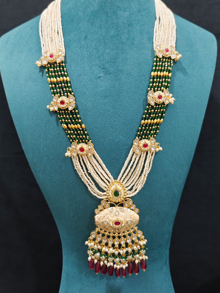 Close-up of an ornate traditional Ruby Pink and Green Rajwadi gold Long jewellery set and earrings  with Pearls, Beads, Meenakari and Moissanite Kundan. Festive look completed with a luxury Rajwadi imitation necklace. Close-up of a premium Rajwadi artificial necklace under 10000.