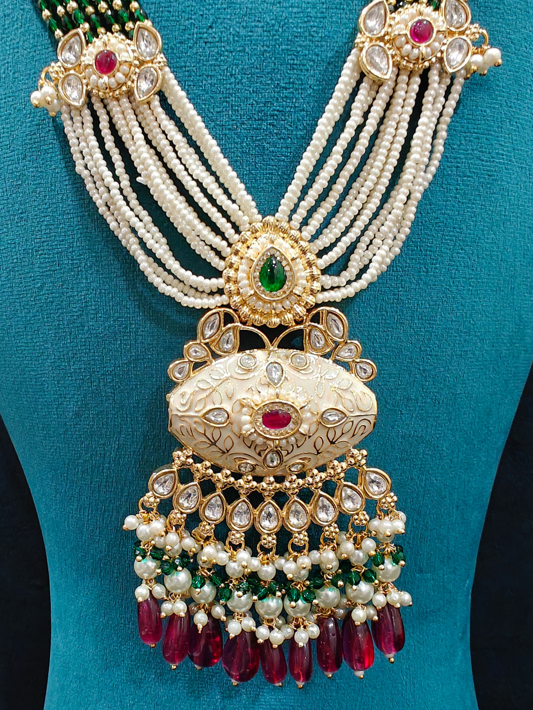 Close-up of an ornate traditional Ruby Pink and Green Rajwadi gold Long jewellery set and earrings  with Pearls, Beads, Meenakari and Moissanite Kundan. Festive look completed with a luxury Rajwadi imitation necklace. Close-up of a premium Rajwadi artificial necklace under 10000.