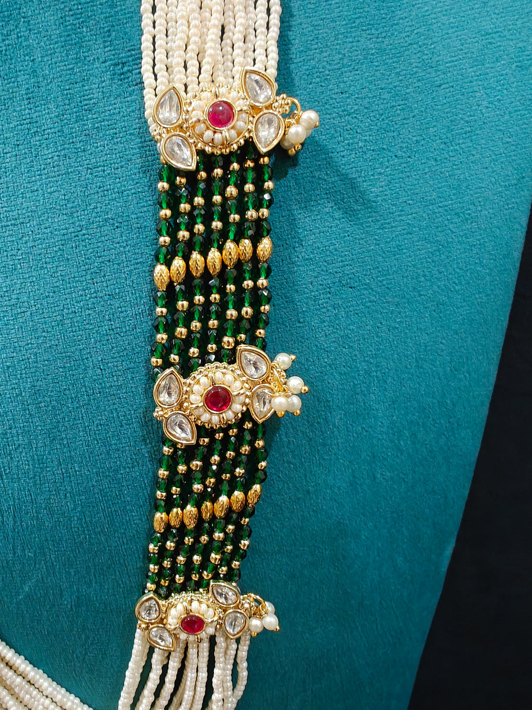 Close-up of an ornate traditional Ruby Pink and Green Rajwadi gold Long jewellery set and earrings  with Pearls, Beads, Meenakari and Moissanite Kundan. Festive look completed with a luxury Rajwadi imitation necklace. Close-up of a premium Rajwadi artificial necklace under 10000.