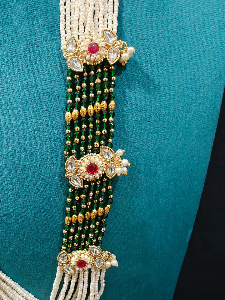 Close-up of an ornate traditional Ruby Pink and Green Rajwadi gold Long jewellery set and earrings  with Pearls, Beads, Meenakari and Moissanite Kundan. Festive look completed with a luxury Rajwadi imitation necklace. Close-up of a premium Rajwadi artificial necklace under 10000.