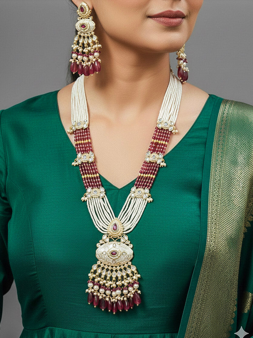 Close-up of a woman wearing an ornate traditional Ruby Pink Rajwadi gold Long jewellery set and earrings  with Pearls, Beads, Meenakari and Moissanite Kundan. Woman wearing a Rajwadi necklace for a reception function. Luxury imitation Rajwadi necklace worn for wedding celebrations.