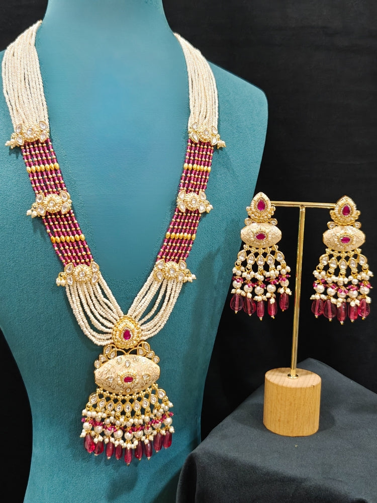 Close-up of an ornate traditional Ruby Pink Rajwadi gold Long jewellery set and earrings  with Pearls, Beads, Meenakari and Moissanite Kundan. Festive look completed with a luxury Rajwadi imitation necklace. Luxury imitation Rajwadi necklace worn for wedding celebrations.