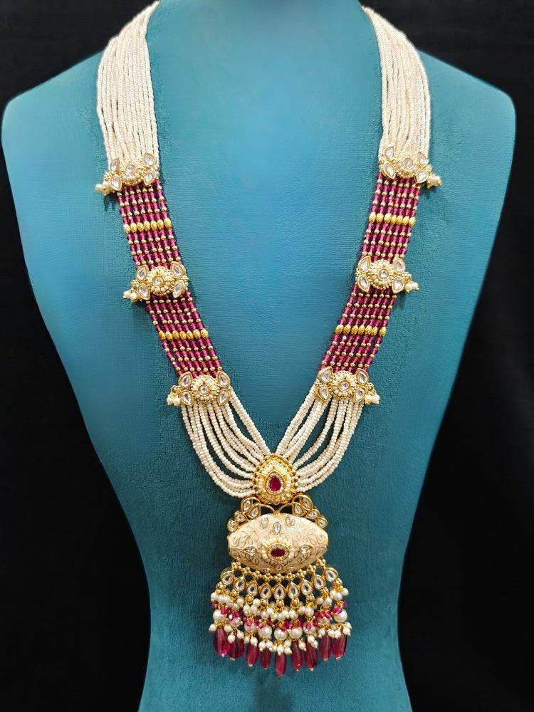 Close-up of an ornate traditional Ruby Pink Rajwadi gold Long jewellery set and earrings  with Pearls, Beads, Meenakari and Moissanite Kundan. Festive look completed with a luxury Rajwadi imitation necklace. Luxury imitation Rajwadi necklace worn for wedding celebrations.