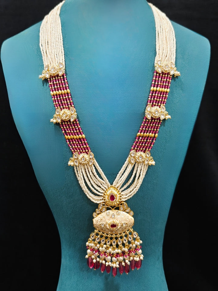 Close-up of an ornate traditional Ruby Pink Rajwadi gold Long jewellery set and earrings  with Pearls, Beads, Meenakari and Moissanite Kundan. Festive look completed with a luxury Rajwadi imitation necklace. Luxury imitation Rajwadi necklace worn for wedding celebrations.