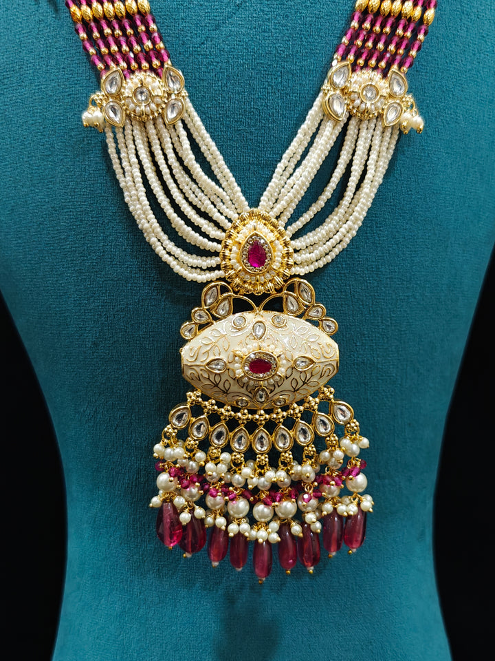 Close-up of an ornate traditional Ruby Pink Rajwadi gold Long jewellery set and earrings  with Pearls, Beads, Meenakari and Moissanite Kundan. Festive look completed with a luxury Rajwadi imitation necklace. Luxury imitation Rajwadi necklace worn for wedding celebrations.