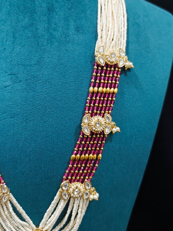 Close-up of an ornate traditional Ruby Pink Rajwadi gold Long jewellery set and earrings  with Pearls, Beads, Meenakari and Moissanite Kundan. Festive look completed with a luxury Rajwadi imitation necklace. Luxury imitation Rajwadi necklace worn for wedding celebrations.