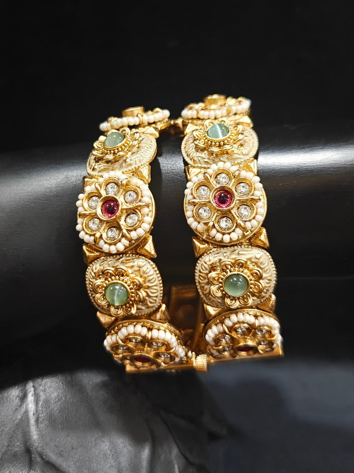 Close-up of an ornate traditional Rajwadi gold Bangle with Red & Mint Green Colored Stone, Bandhai Work and Meenakari. Festive celebration look enhanced with statement artificial  Rajwadi bangles. Perfect Rajwadi Bangles for weddings and festivals. Festive Diwali outfit paired with a colorful Meenakari Bangles.