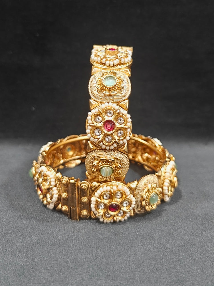 Close-up of an ornate traditional Rajwadi gold Bangle with Red & Mint Green Colored Stone, Bandhai Work and Meenakari. Festive celebration look enhanced with statement artificial  Rajwadi bangles. Perfect Rajwadi Bangles for weddings and festivals. Festive Diwali outfit paired with a colorful Meenakari Bangles.