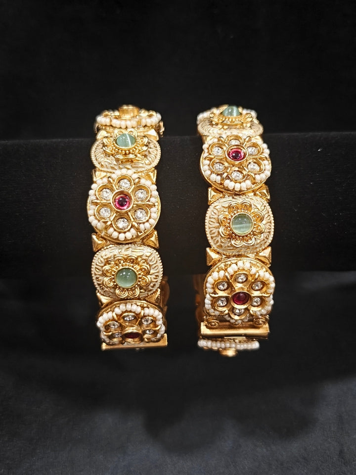 Close-up of an ornate traditional Rajwadi gold Bangle with Red & Mint Green Colored Stone, Bandhai Work and Meenakari. Festive celebration look enhanced with statement artificial  Rajwadi bangles. Perfect Rajwadi Bangles for weddings and festivals. Festive Diwali outfit paired with a colorful Meenakari Bangles.