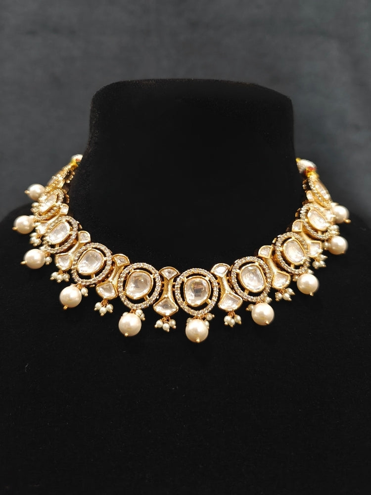 Close-up of an ornate traditional (Gold Polish) Collar jewellery set and earrings with Polki, American Diamond and Pearls. Festive saree look completed with a Polki artificial jewelry set. Woman wearing a lightweight Polki jewelry set for long wedding functions.