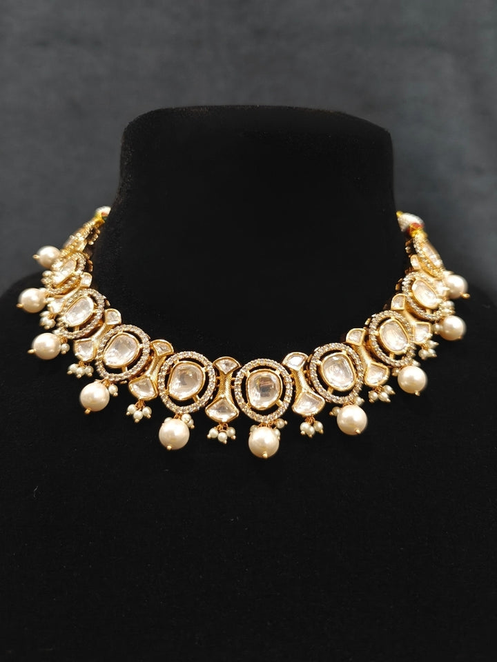 Close-up of an ornate traditional (Gold Polish) Collar jewellery set and earrings with Polki, American Diamond and Pearls. Festive saree look completed with a Polki artificial jewelry set. Woman wearing a lightweight Polki jewelry set for long wedding functions.