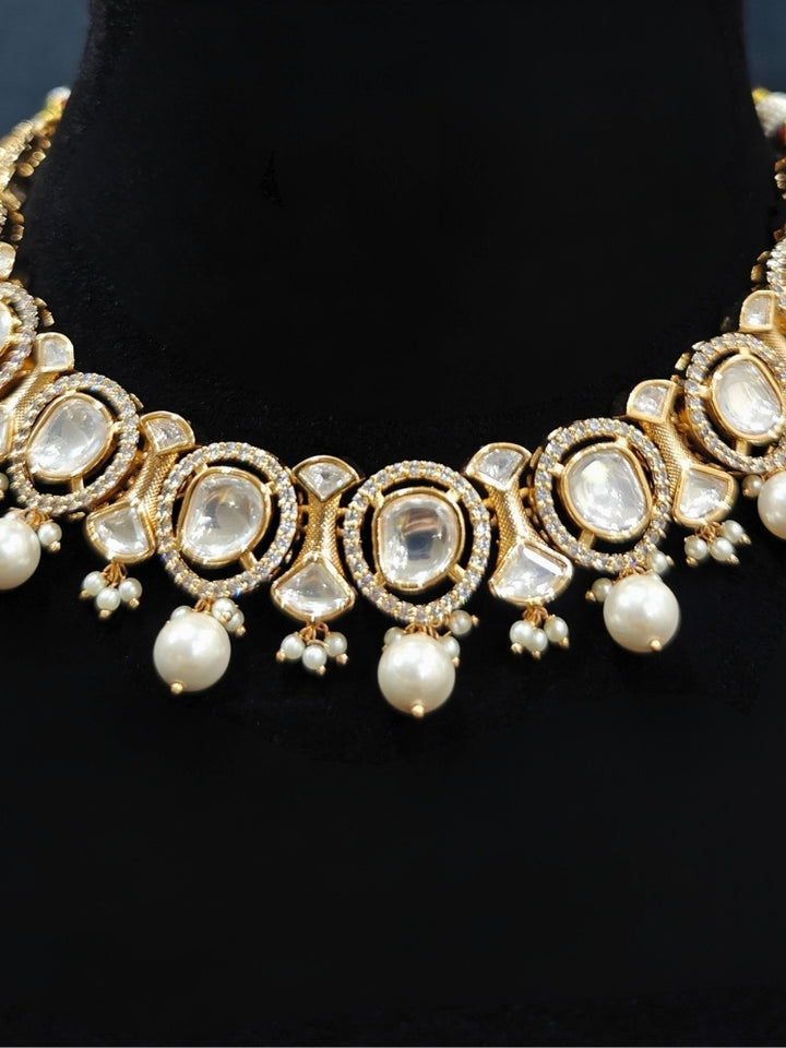 Close-up of an ornate traditional (Gold Polish) Collar jewellery set and earrings with Polki, American Diamond and Pearls. Festive saree look completed with a Polki artificial jewelry set. Woman wearing a lightweight Polki jewelry set for long wedding functions.