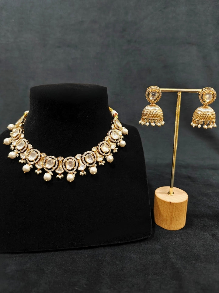 Close-up of an ornate traditional (Gold Polish) Collar jewellery set and earrings with Polki, American Diamond and Pearls. Festive saree look completed with a Polki artificial jewelry set. Woman wearing a lightweight Polki jewelry set for long wedding functions.