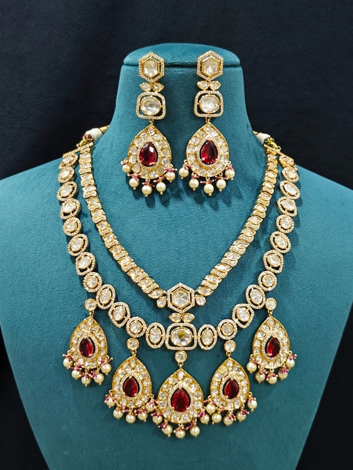 Close-up of an ornate traditional (Gold Polish) Layered Red jewellery set and earrings with Polki, American Diamond and Red Colored stones. Woman styling a premium Polki imitation necklace for wedding celebrations. Festive celebration look completed with premium imitation Polki jewelry.