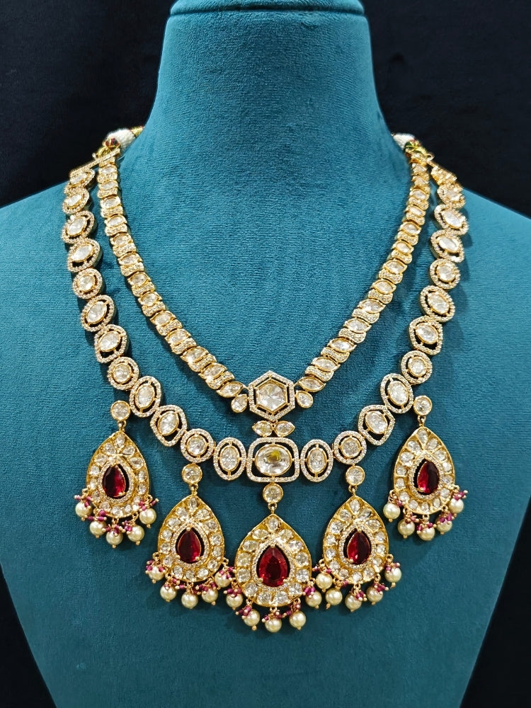 Close-up of an ornate traditional (Gold Polish) Layered Red jewellery set and earrings with Polki, American Diamond and Red Colored stones. Woman styling a premium Polki imitation necklace for wedding celebrations. Festive celebration look completed with premium imitation Polki jewelry.