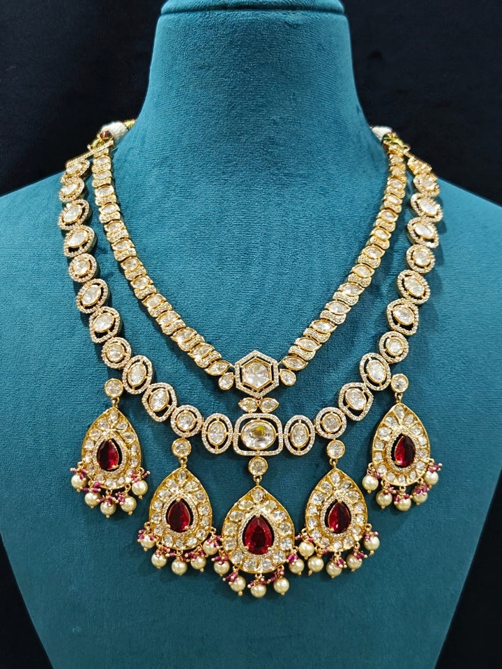 Close-up of an ornate traditional (Gold Polish) Layered Red jewellery set and earrings with Polki, American Diamond and Red Colored stones. Woman styling a premium Polki imitation necklace for wedding celebrations. Festive celebration look completed with premium imitation Polki jewelry.