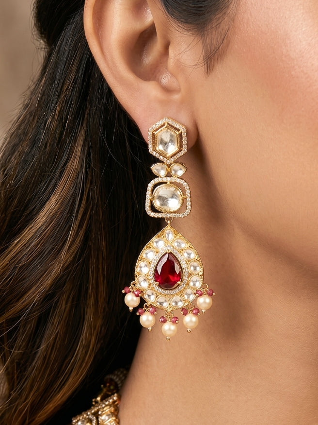 Close-up of a woman wearing an ornate traditional (Gold Polish) Layered Red jewellery set and earrings with Polki, American Diamond and Red Colored stones. Woman styling a premium Polki imitation necklace for wedding celebrations. Festive celebration look completed with premium imitation Polki jewelry.