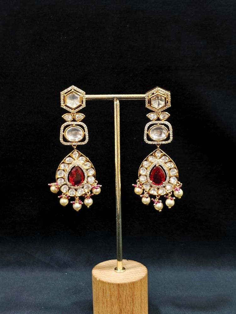 Close-up of an ornate traditional (Gold Polish) Layered Red jewellery set and earrings with Polki, American Diamond and Red Colored stones. Woman styling a premium Polki imitation necklace for wedding celebrations. Festive celebration look completed with premium imitation Polki jewelry.