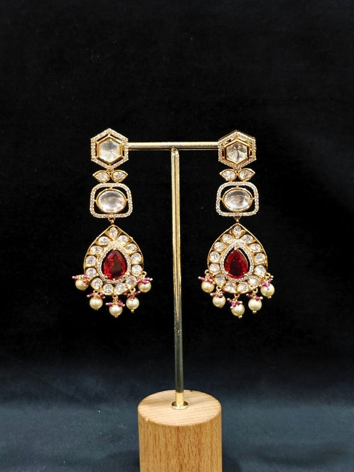 Close-up of an ornate traditional (Gold Polish) Layered Red jewellery set and earrings with Polki, American Diamond and Red Colored stones. Woman styling a premium Polki imitation necklace for wedding celebrations. Festive celebration look completed with premium imitation Polki jewelry.