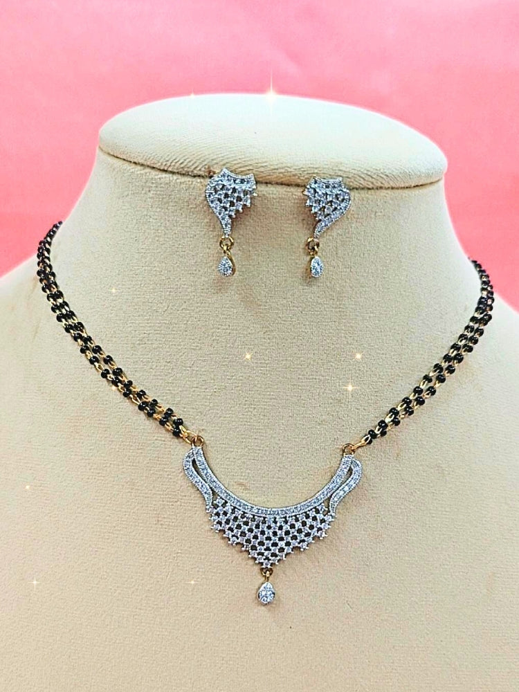 Simmi Mangalsutra—a gold necklace with black mangalsutra beads and matching earrings, pendant featuring sparkling American Diamonds—set against a cream dummy, perfect for your wedding ceremony dress. Diamond mangalsutra. Modern mangalsutra. 