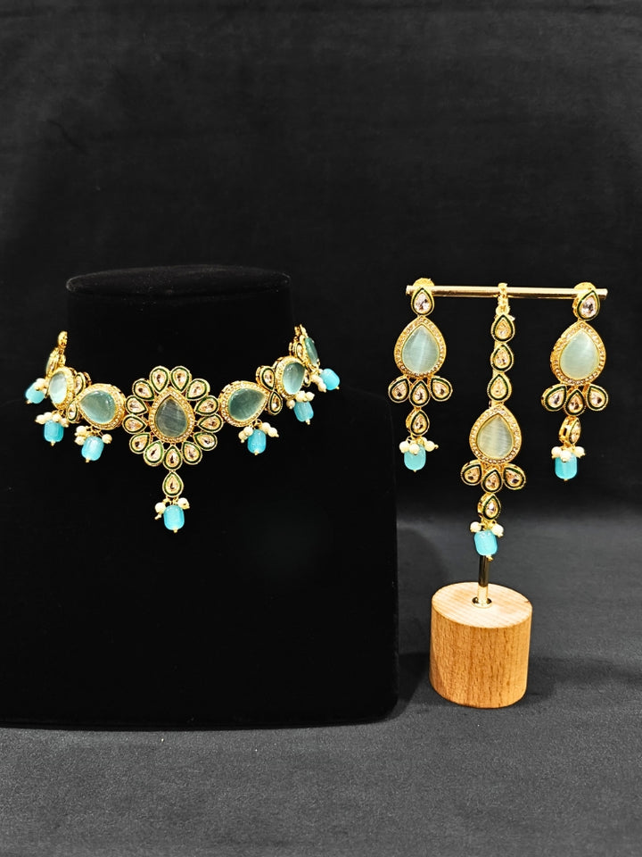 Close-up of an ornate traditional Sky Blue Choker jewellery set and earrings and maangtikka with Kundan, Monalisa Stone, American Diamonds, Beads and Reverse American Diamonds and tumble stones. A graceful woman wearing a trending Colored Stone necklace for a 2026 wedding celebration. Elegant wedding jewelry look featuring a premium artificial Colored Stone necklace.