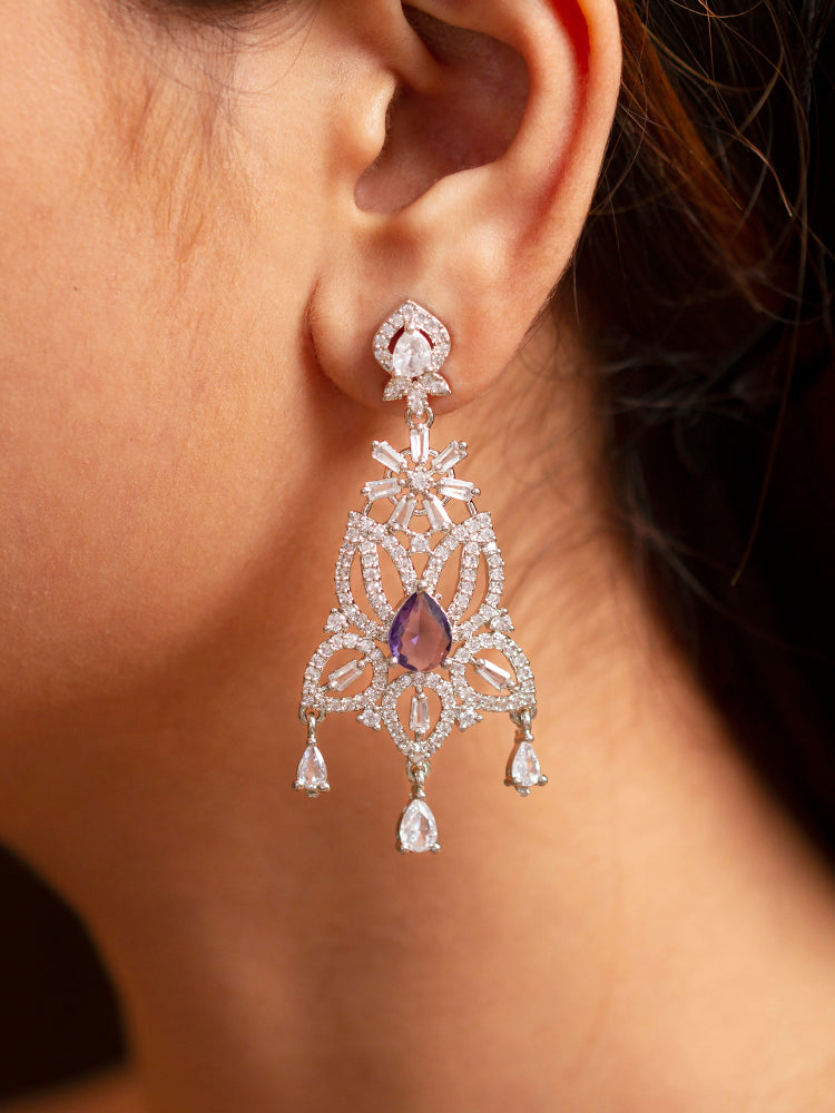 Close-up of a woman wearing an ornate Western (Silver Polish) Purple Diamond Earrings with American Diamond and Colored Stones. Woman wearing statement artificial American Diamond earrings for a wedding guest look in India. Elegant party wear styled with high-quality imitation American Diamond earrings.