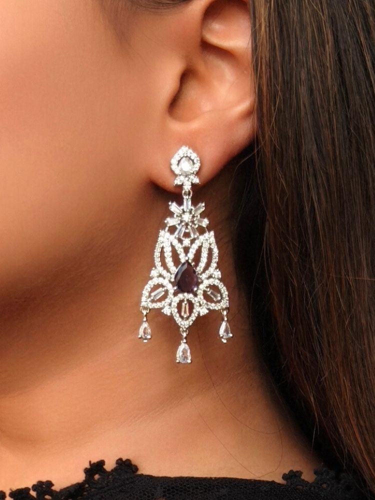 Close-up of a woman wearing an ornate Western (Silver Polish) Purple Diamond Earrings with American Diamond and Colored Stones. Woman wearing statement artificial American Diamond earrings for a wedding guest look in India. Elegant party wear styled with high-quality imitation American Diamond earrings.