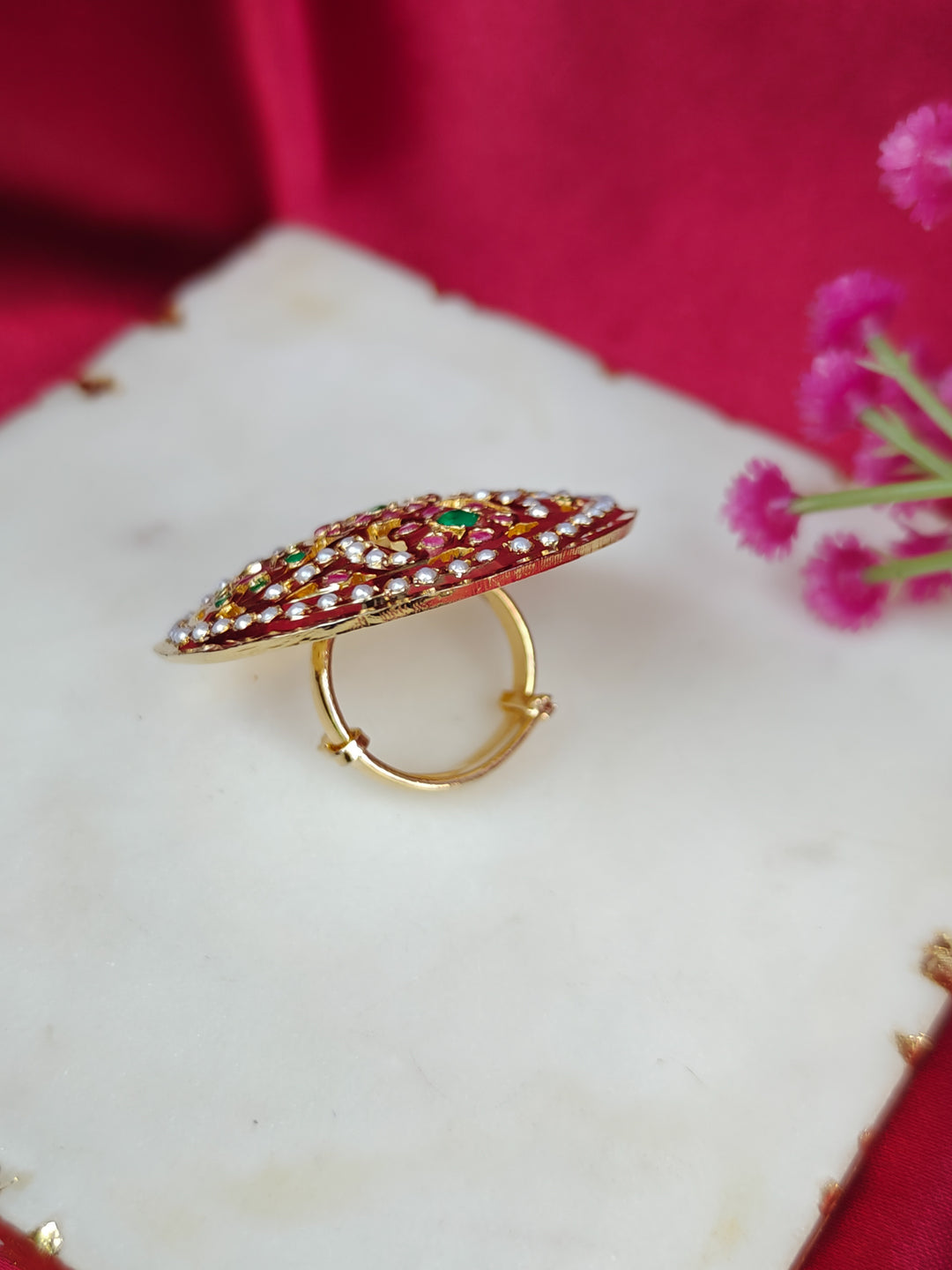 Close-up of an ornate traditional White, Multi-color jadau gold Ring with pearl and Color Stone. Woman wearing a trendy artificial Jadau ring for wedding season in India. Festive Diwali look completed with a artificial Jadau ring.