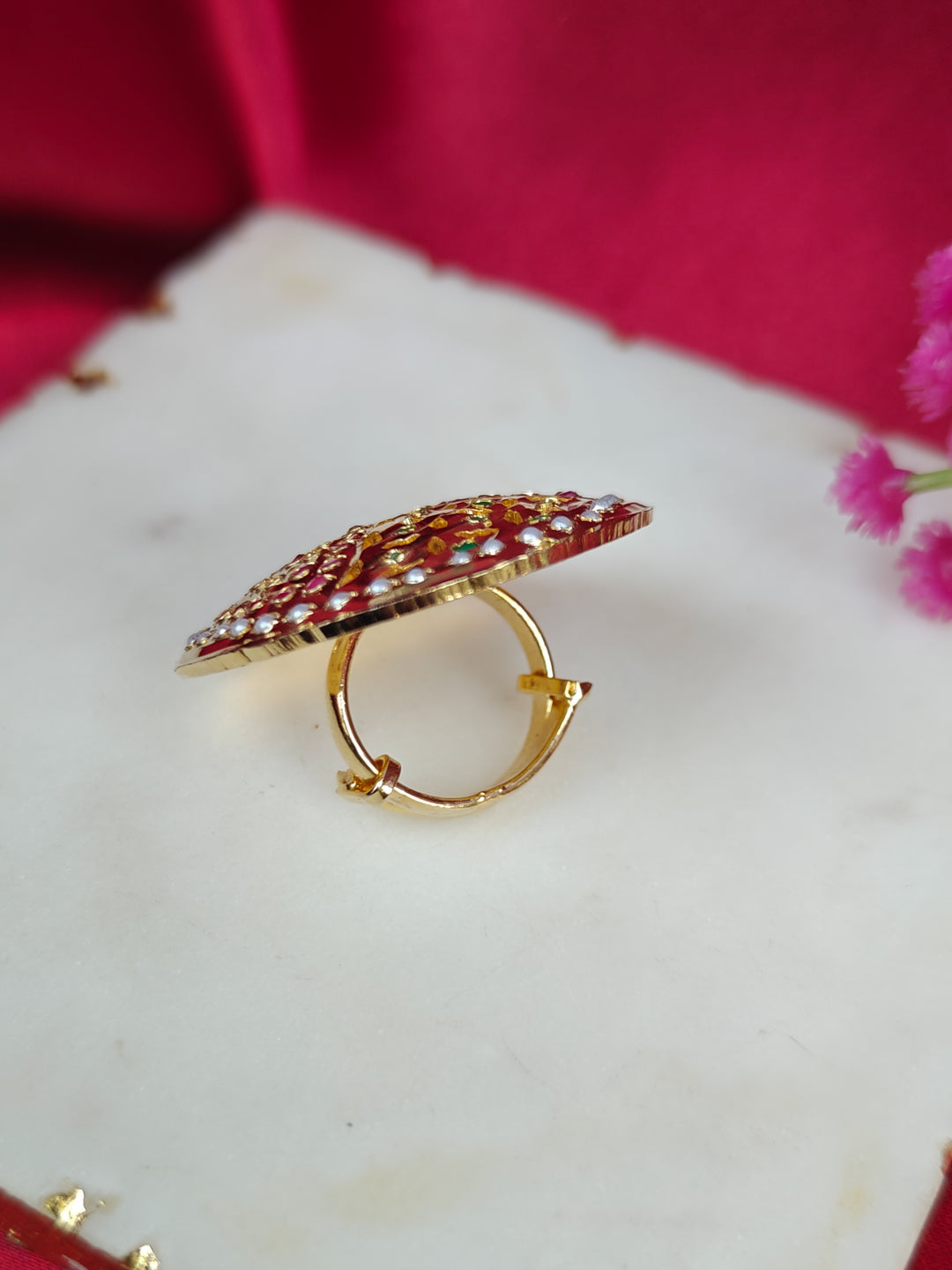 Close-up of an ornate traditional White, Multi-color jadau gold Ring with pearl and Color Stone. Styling a premium imitation jadau ring with festive attire. Close-up of a high-quality imitation jadau ring with intricate detailing.
