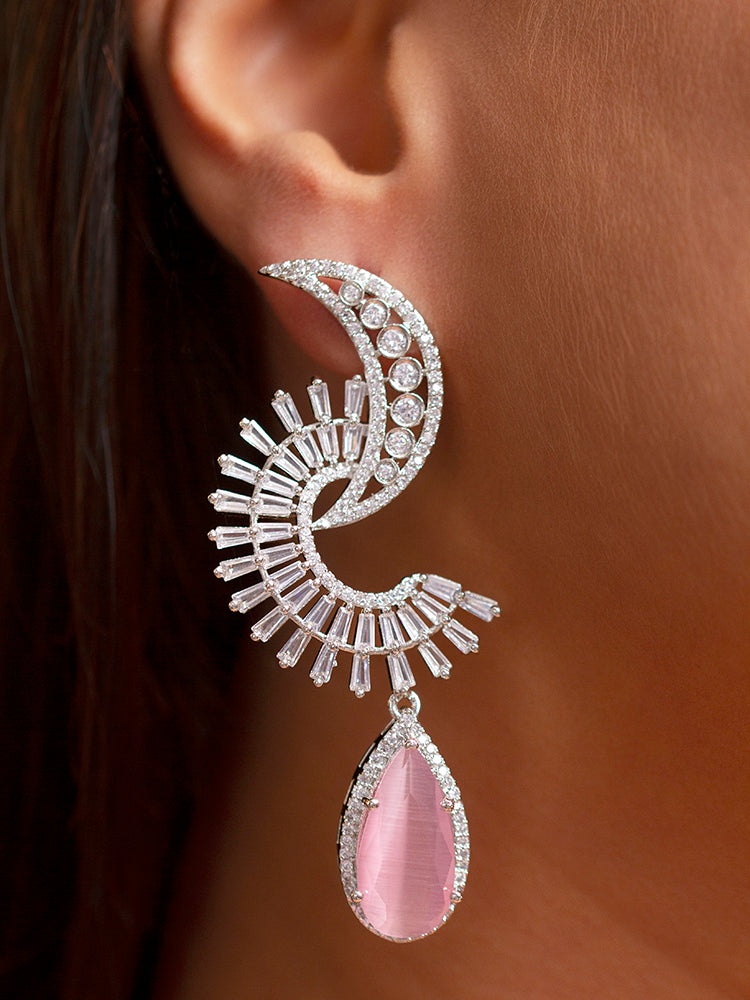 Close-up of a woman wearing an ornate Western (Silver Polish) Pink Long Diamond  Earrings with American Diamond and Pink Colored Stones. Cocktail party outfit paired with sparkling artificial American Diamond earrings. Reception-ready look completed with statement artificial American Diamond jewelry earrings.