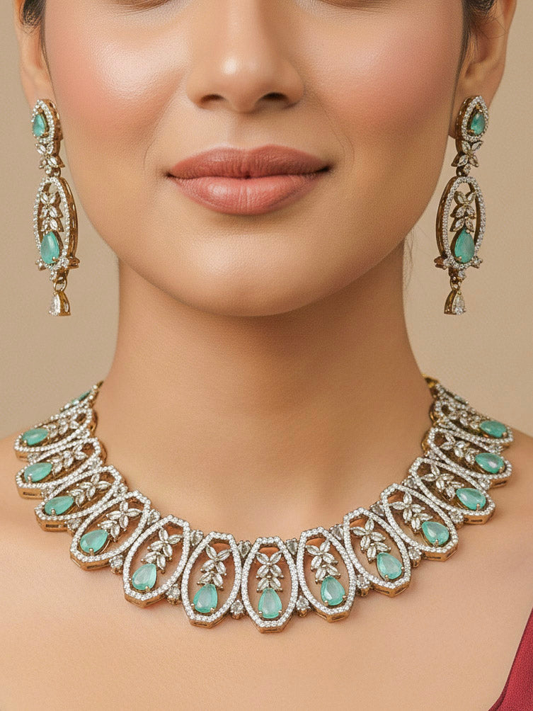 Close-up of a woman wearing an ornate Indo-Western American diamond and Colored Stone Collar jewellery set and earrings and maangtikka with American diamond and Colored Stone. A woman wearing a luxury American diamond necklace set styled beautifully for a wedding guest look in India.