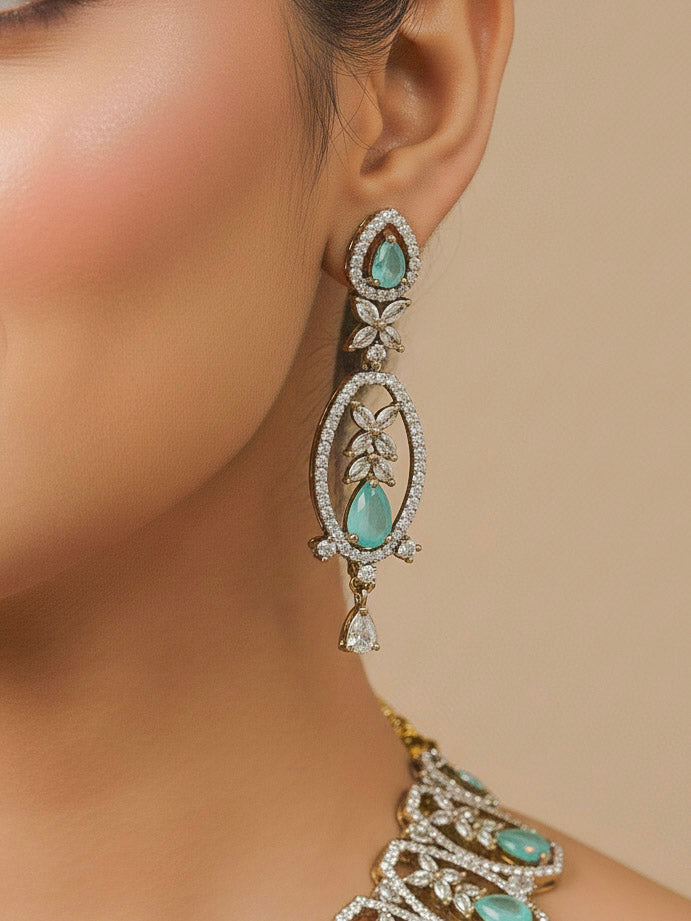 Close-up of a woman wearing an ornate Indo-Western American diamond and Colored Stone Collar jewellery set and earrings and maangtikka with American diamond and Colored Stone. A woman wearing a luxury American diamond necklace set styled beautifully for a wedding guest look in India.