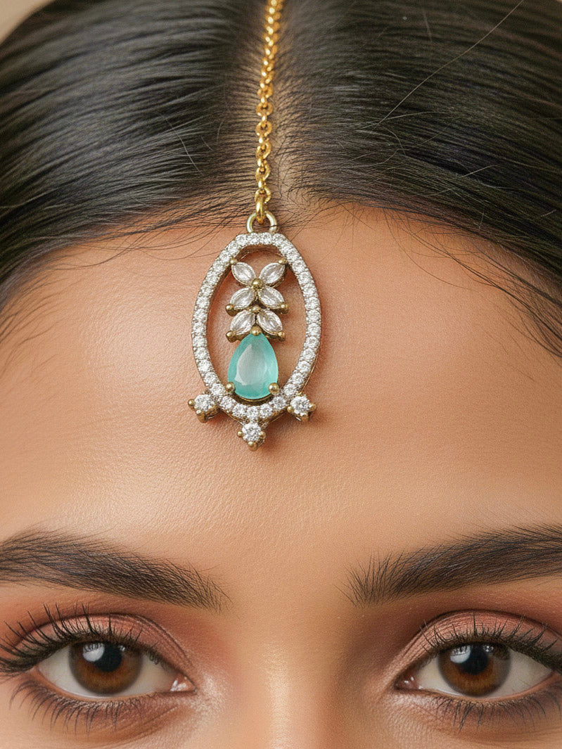 Close-up of a woman wearing an ornate Indo-Western American diamond and Colored Stone Collar jewellery set and earrings and maangtikka with American diamond and Colored Stone. A woman wearing a luxury American diamond necklace set styled beautifully for a wedding guest look in India.