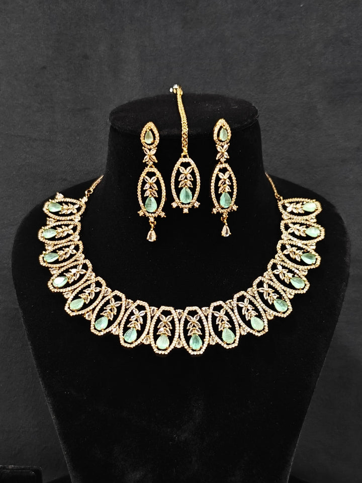 Close-up of an ornate Indo-Western American diamond and Colored Stone Collar jewellery set, earrings and maangtikka with American diamond and Colored Stone. A sparkling American diamond necklace for reception night.