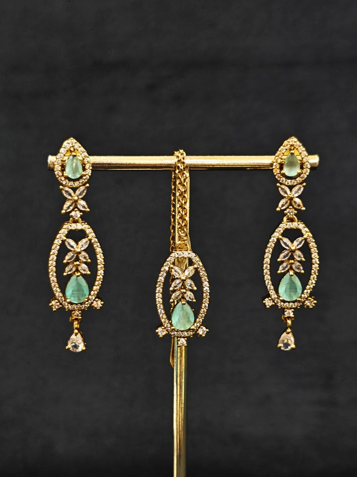 Close-up of an ornate Indo-Western American diamond and Colored Stone Collar jewellery set, earrings and maangtikka with American diamond and Colored Stone. A sparkling American diamond necklace for reception night.