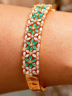 Close-up of a woman wearing an ornate Traditional (Gold Polish) Green Bracelet with American Diamond and Colored Stones. Festive outfit paired with a premium imitation American Diamond bracelet in India. Close-up of skin-friendly artificial jewelry American Diamond bracelet in India.