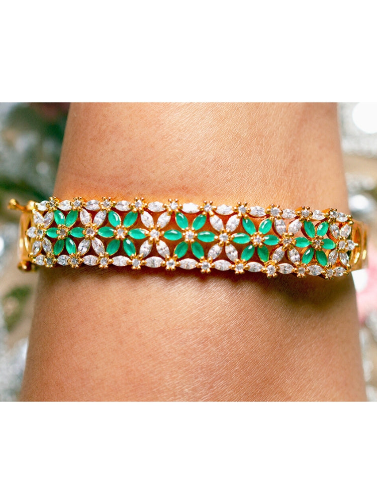 Close-up of a woman wearing an ornate Traditional (Gold Polish) Green Bracelet with American Diamond and Colored Stones. Festive outfit paired with a premium imitation American Diamond bracelet in India. Close-up of skin-friendly artificial jewelry American Diamond bracelet in India.