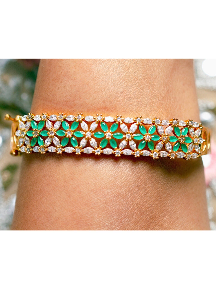 Close-up of a woman wearing an ornate Traditional (Gold Polish) Green Bracelet with American Diamond and Colored Stones. Festive outfit paired with a premium imitation American Diamond bracelet in India. Close-up of skin-friendly artificial jewelry American Diamond bracelet in India.