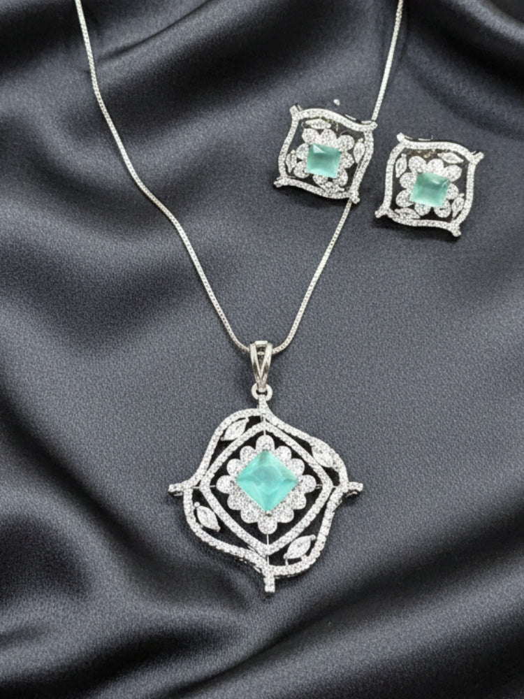 Close-up of an ornate Western (Silver Polish) Mint Green Diamond Pendant set and earrings with American Diamond and Colored Stones. Party wear outfit completed with a lightweight American diamond Pendant Set. Close-up shot of a high-quality American diamond artificial Pendant worn for festive celebrations.
